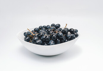 Bunches of blue grapes in a white plate on a white background. Berries, summer harvest, healthy eating