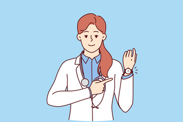Woman doctor points to wristwatch reminding of medication schedule or time to visit clinic. Girl doctor in white coat with stethoscope around neck smiles reporting hospital opening hours
