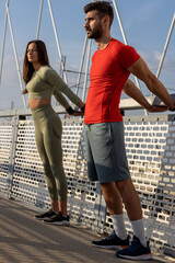 Couple of two friends exercise and stretch before jogging on the bridge