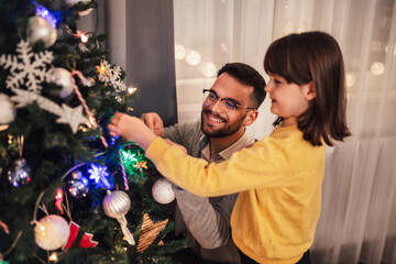 Loving father celebrates Christmas with his daughter by the beautiful Christmas tree