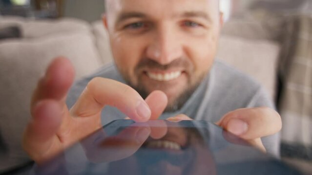 Close up funny male scrolling touchpad screen on smartphone in living room at home. Close-up comic bearded crazy hilarious man making silly funny eye and brows moves. Curious nerd search.Humor concept