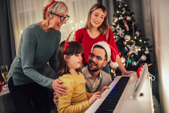 Family while enjoying music that their daughter playing on piano during Christmas time