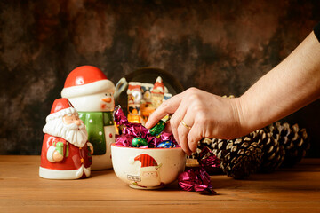 A hand taking a sweet from a bowl with Christmas motifs.