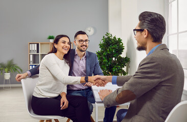 Portrait of a happy couple shaking hands with a male business broker or insurance agent. Cheerful...