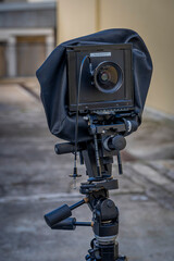 View of a black bellows camera attached to a photo stand in an outdoor courtyard