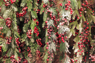 Artificial Christmas tree branches with clusters of red berries, artificial snow. New Year's decor. Close-up of Christmas tree decorations. Selling New Year's decor in a supermarket