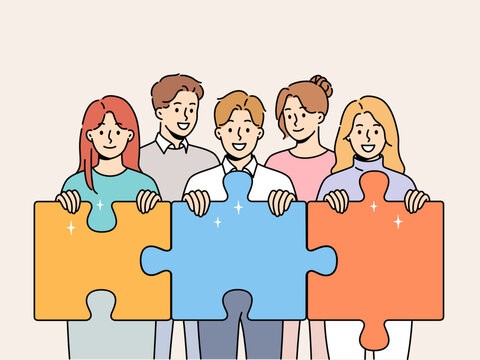 Friendly team of men and women hold giant puzzle pieces symbolizing working together to solve business problems. Business people with smile doing teamwork to increase company income