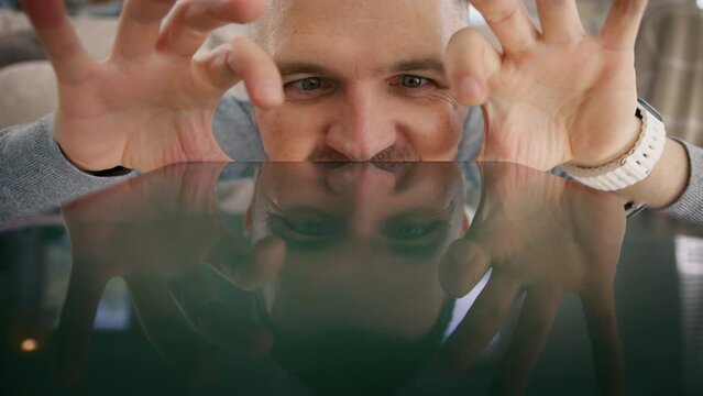 Comic man making silly funny faces using fingers of both hands like spider to search online. Humor Curious nerd search. Funny male looks closely on tablet devise screen trying to find information web