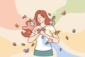 Happy woman puts hands on chest standing among flying butterflies and petals symbolizing spring mood. Cheerful girl experiences positive emotions and good mood thanks to onset of spring