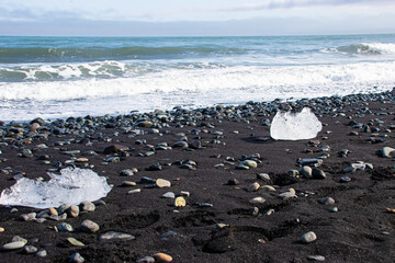 Ice floes on black volcanic sand on Diamond Beach in Iceland on a sunny day while travelling