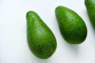 Ripe juicy avocado fruit on a white background. Vegetarian vegetables. Green fruits.