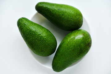 Ripe juicy avocado fruit on a white background. Vegetarian vegetables. Green fruits.