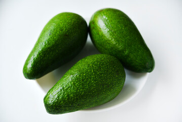 Ripe juicy avocado fruit on a white background. Vegetarian vegetables. Green fruits.