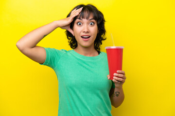 Young Argentinian woman holding a soda isolated on yellow background with surprise expression