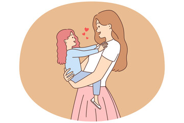 Smiling mother holding small daughter in hands