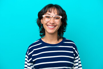 Young Argentinian woman isolated on blue background With glasses with happy expression
