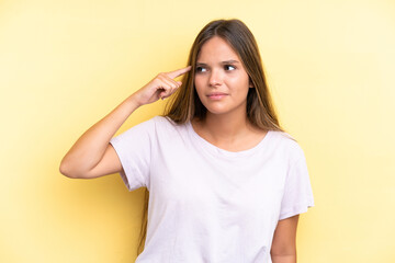 Young caucasian woman isolated on yellow background making the gesture of madness putting finger on...