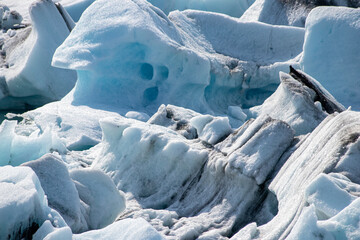 Glacier erosions in Iceland with black volcanic dust on the ice on a cold day in spring, climate crisis, Glacial lake