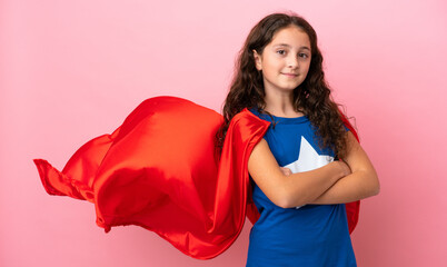 Little caucasian girl isolated on pink background in superhero costume with arms crossed