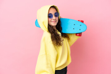 Little caucasian girl isolated on pink background with a skate with happy expression