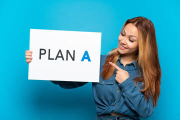 Teenager girl over isolated blue background holding a placard with the message PLAN A and  pointing it