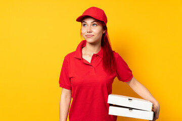 Pizza delivery girl holding a pizza over isolated background and looking up