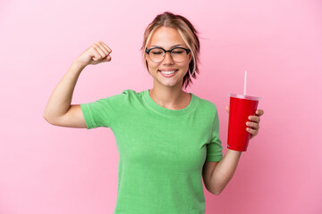 Young Russian woman holding a refreshment isolated on pink background doing strong gesture