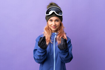 Skier teenager girl with snowboarding glasses over isolated purple background making money gesture