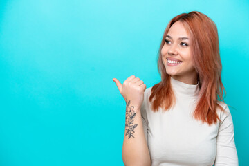 Young Russian woman isolated on blue background pointing to the side to present a product