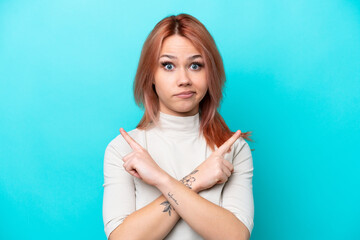Young Russian woman isolated on blue background pointing to the laterals having doubts