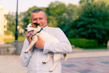 portrait of an adult bearded man holding his little dog of the Jack Russell Terrier breed caring...
