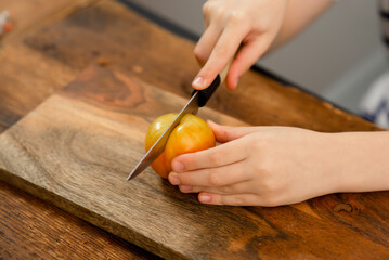 Obraz na płótnie Canvas Plum perfection: A boy skillfully cutting a succulent, golden plum on a rustic wooden surface