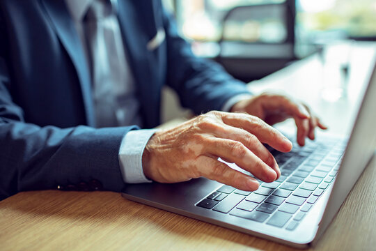 Close-up of a Businessman's Hands Typing on a Laptop Keyboard
