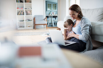 Little girl daughter using laptop with mother at home