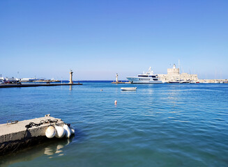 Port of Mandraki with Rhodean deers statues on the two columns at the entrance and the Saint Nicholas Fortress. Dodecanese, Rhodes Island, Greece.