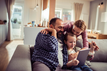 Family with little daughter watching tablet at home