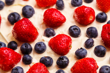 Fresh juicy strawberries and blueberries blueberries in thick whipped cream close-up
