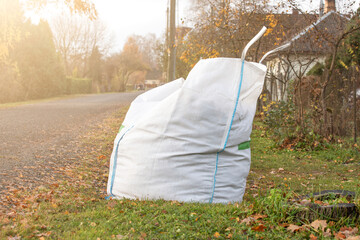 Big white bag filled with organic green garden waste after gardening