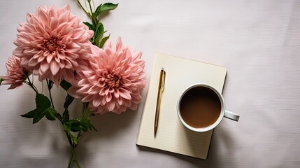  a cup of coffee next to a notepad with a pen on top of it and a bouquet of pink flowers.