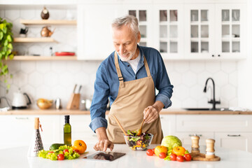 Cheerful Senior Man Cooking Food In Kitchen And Using Digital Tablet