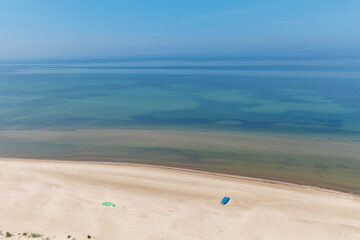 Aerial landscape of the summer beach with lonely blue fishing boat resting on the sand. Baltic sea, Lithuania