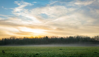 Scenic view of a morning mist over the field with a sunrise sky