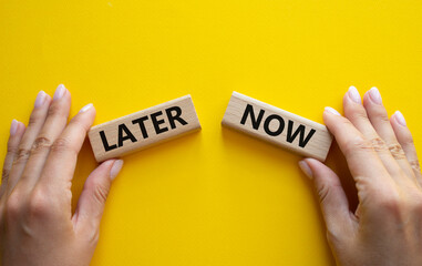 Now vs Later symbol. Concept word Now vs Later on wooden blocks. Businessman hand. Beautiful yellow background. Business and Now vs Later concept. Copy space