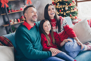 Photo of cute small girl cheerful parents sit couch watch tv newyear show enjoy festive time house...
