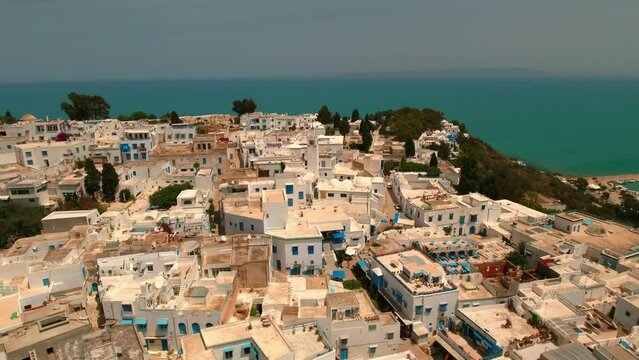 Aerial Panning Scenic Shot Of Buildings In Town On Cliff By Sea, Drone Flying During Sunny Day - Mahdia, Tunisia