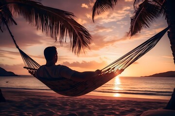 man relaxing in a hammock on the beach at sunset