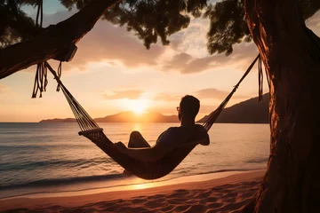 Foto auf Acrylglas man relaxing in a hammock on the beach at sunset © Salsabila Ariadina