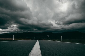 Empty asphalt road on a stormy day - obrazy, fototapety, plakaty
