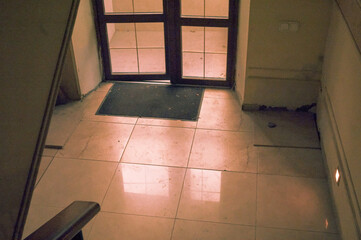 dirty tiled floor and walls in a house entrance with glass doors