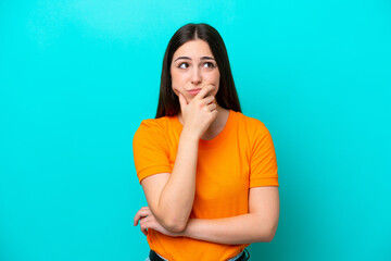 Young caucasian woman isolated on blue background having doubts - obrazy, fototapety, plakaty